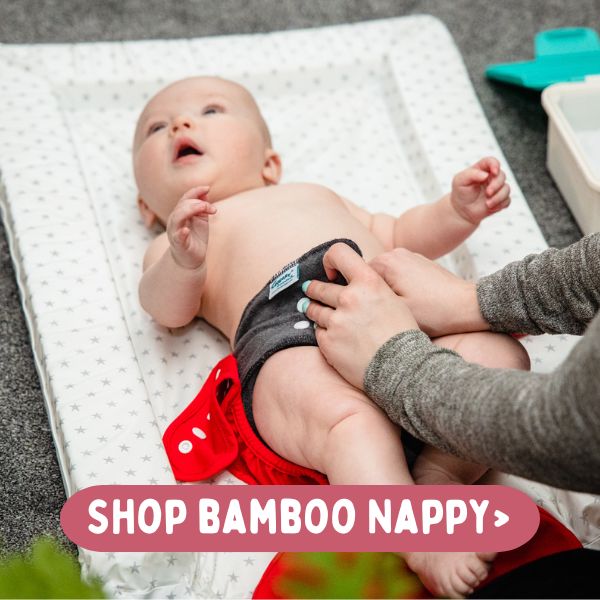 Image of baby being changed in a charcoal fitted cloth nappy and nappy wrap